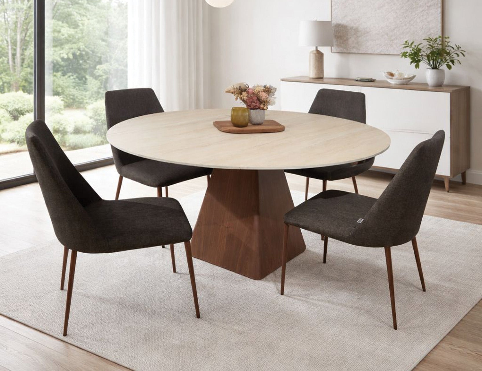 Round dining table with wooden base and four upholstered chairs in modern space