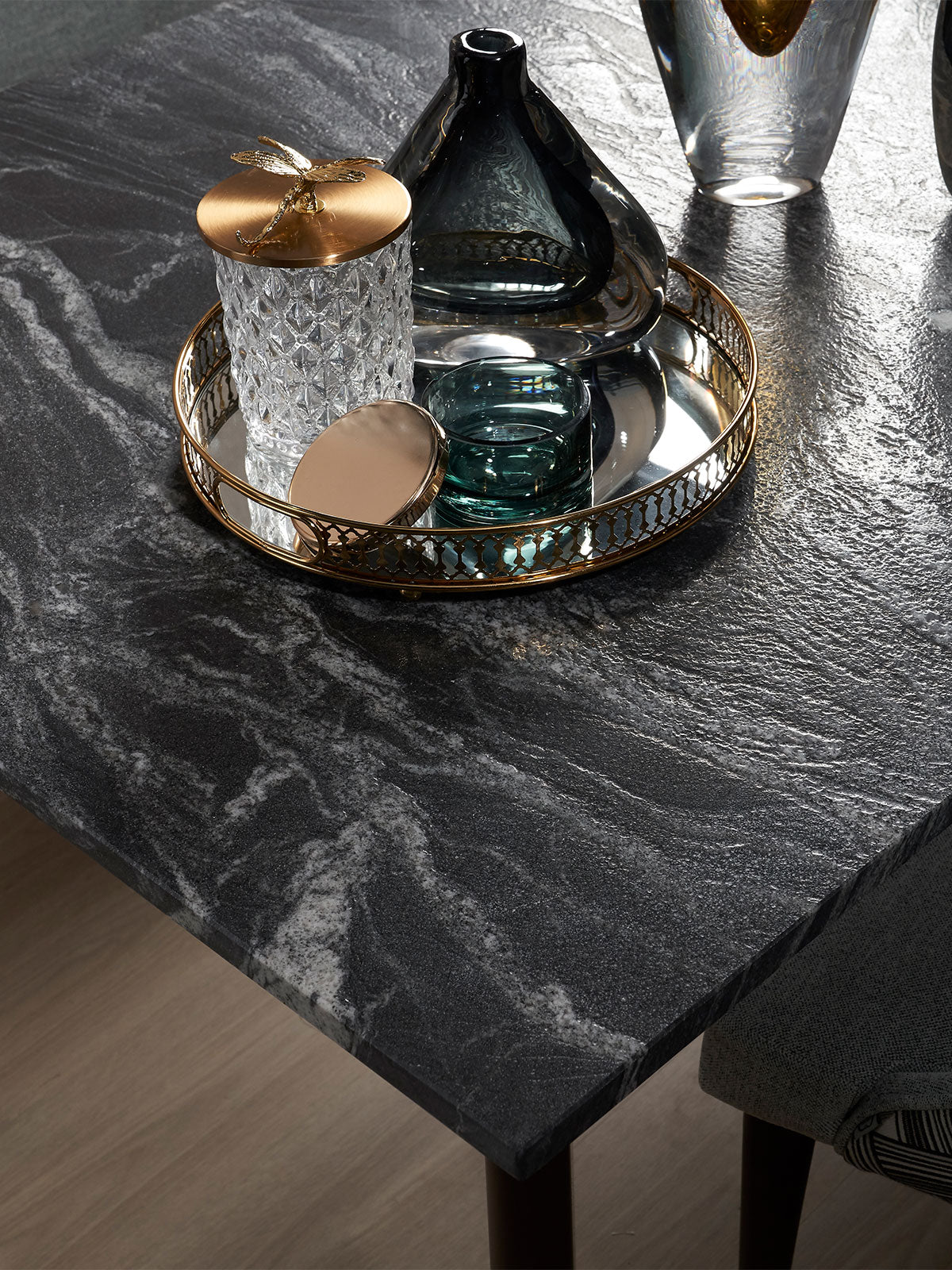 Black marble dining table surface with decorative tray and glassware styling