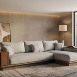 L-shaped sectional sofa in light grey fabric with walnut wood armrest shelf and brushed gold base, styled in a warm Japandi living room